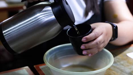 person pours water from thermos into bowl