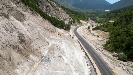 Excavator-on-construction-site-on-mountainside-clearing-dirt-for-new-road-close-to-main-road