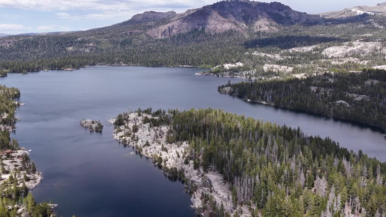 Filmato di drone che sorvola le acque incontaminate del Silver Lake, rivelando una vasta pineta e maestose montagne di granito nella Eldorado National Forest di Pioneer, California, in una giornata di sole.
