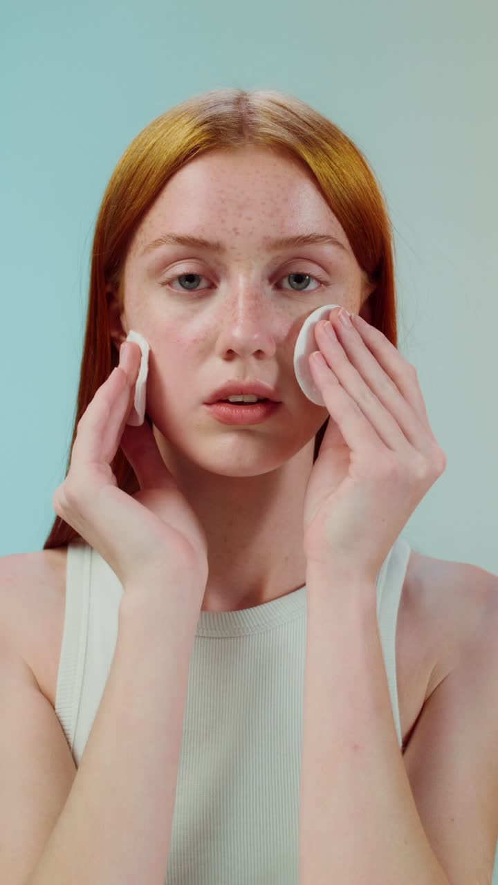 mujer limpiándose la cara con almohadillas de algodón