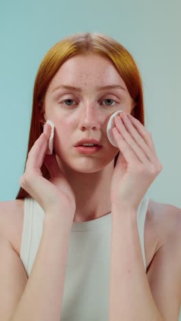 woman cleansing her face with cotton pads