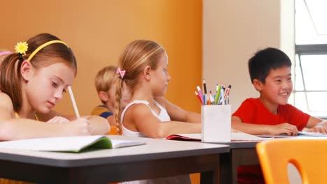 Schoolgirl-whispering-into-her-friends-ear-in-classroom