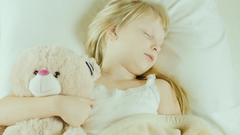 Kleines-Mädchen,-Das-Im-Bett-Schläft,-Kuschelt-Einen-Spielzeugbären-Draufsicht