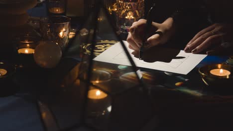 close up of woman drawing astrology lagna or birth chart on candlelit table