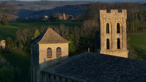 Aeial-shot-of-a-church-in-France,-drone-shot-of-the-steeple-with-a-circular-movement,-pigeons-flying-around-the-steeple,-Saint-Avit-Sénieur-in-Dordogne