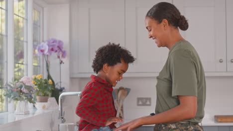 Army-Mother-In-Uniform-Home-On-Leave-Giving-Son-High-Five-In-Family-Kitchen
