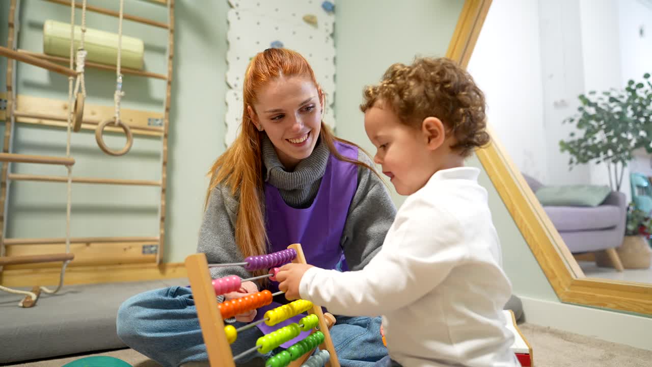 Insegnante felice e bambino piccolo che giocano con un abaco colorato