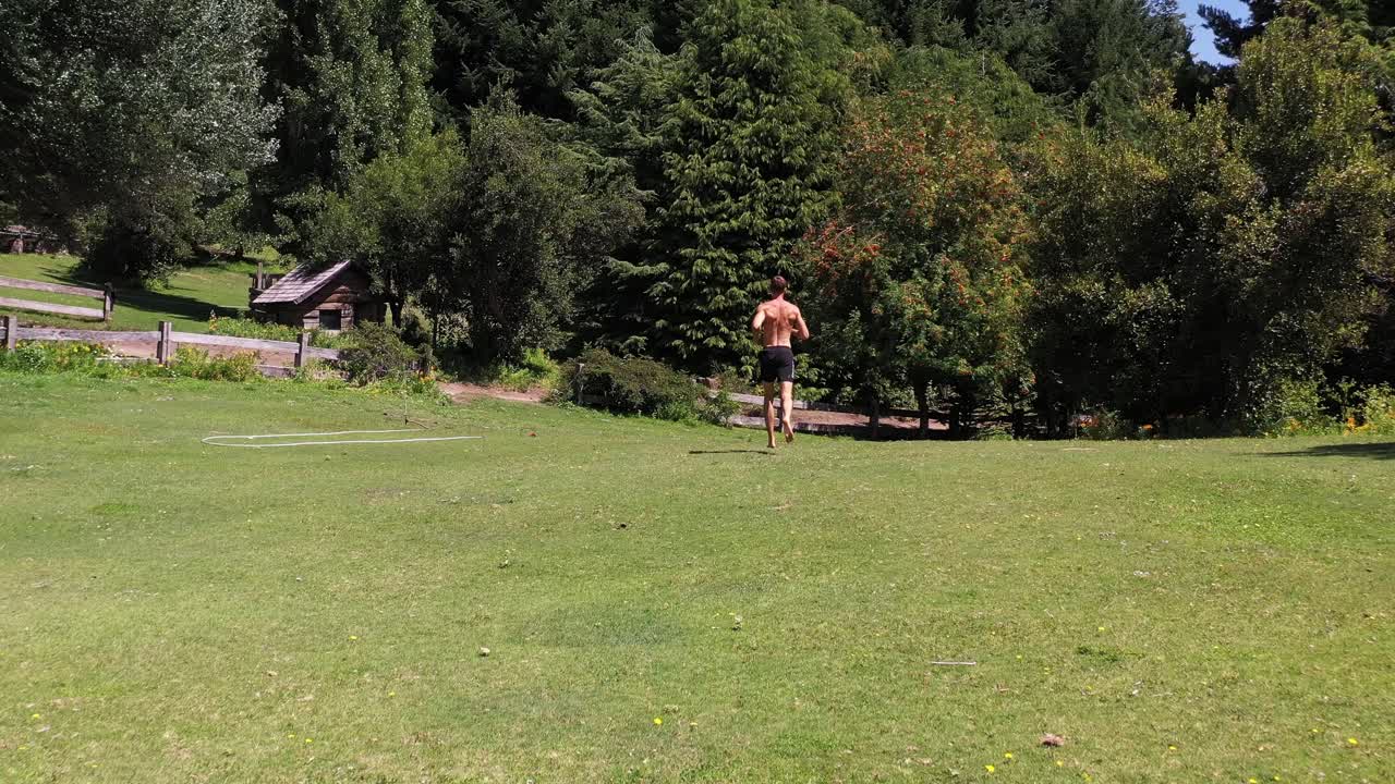 joven caucásico en forma atractiva haciendo ejercicio al aire libre con fondo de vegetación verde en 4k