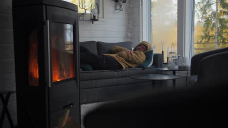 man lying on sofa than a nap in a warm room with a burning stove