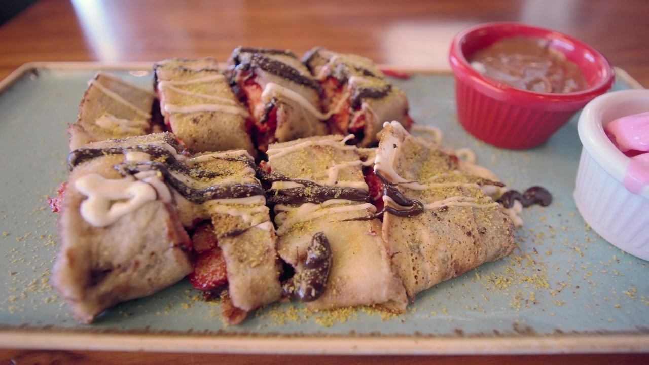 Rollo de crepa de fresa en rebanadas con salsa de chocolate y helado