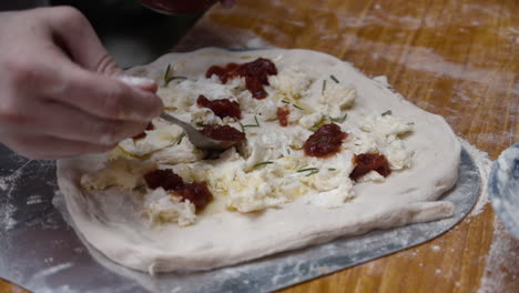 adding spicy chili sauce onto the pizza dough