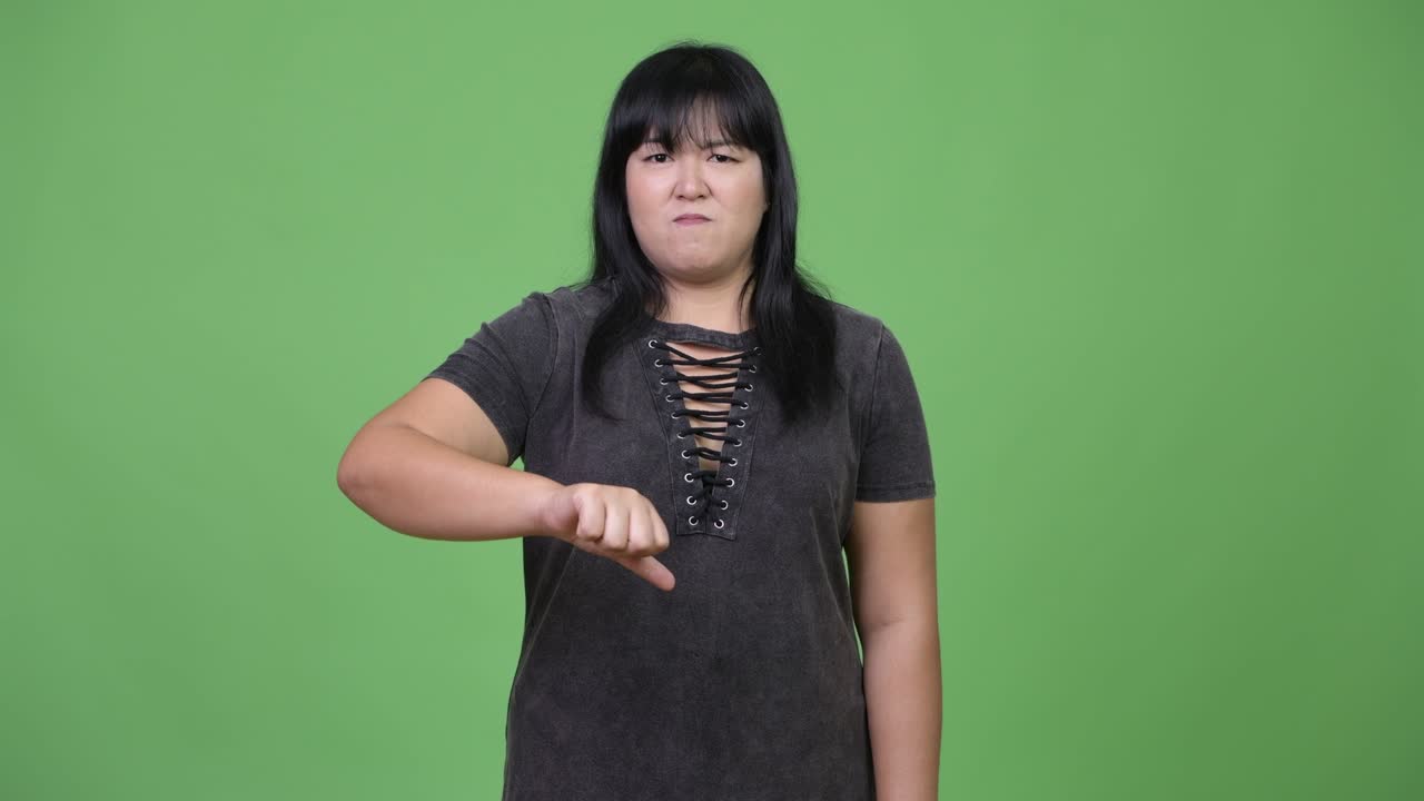 Angry overweight Asian woman giving thumbs down
