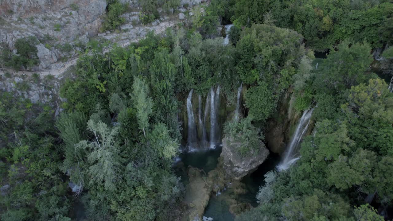 video panorámico descriptivo de drones con cenit y en reversa sobre la cascada manojlovac en el río krka en croacia que termina el horizonte en la montaña