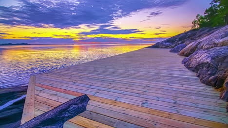 Timelapse-of-the-golden-setting-sun-over-a-wooden-jettie-on-a-tropical-beach-with-sea-water-during-the-evening-time