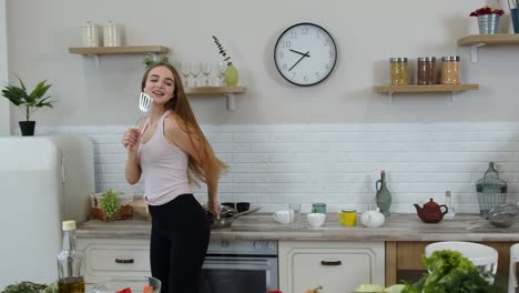 chica vegana feliz con cintura delgada bailando, cantando en la cocina. concepto de dieta de nutrición de verduras crudas