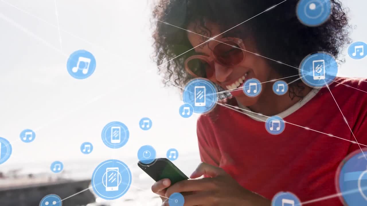 red de iconos digitales contra una mujer afroamericana que usa un teléfono inteligente en la playa