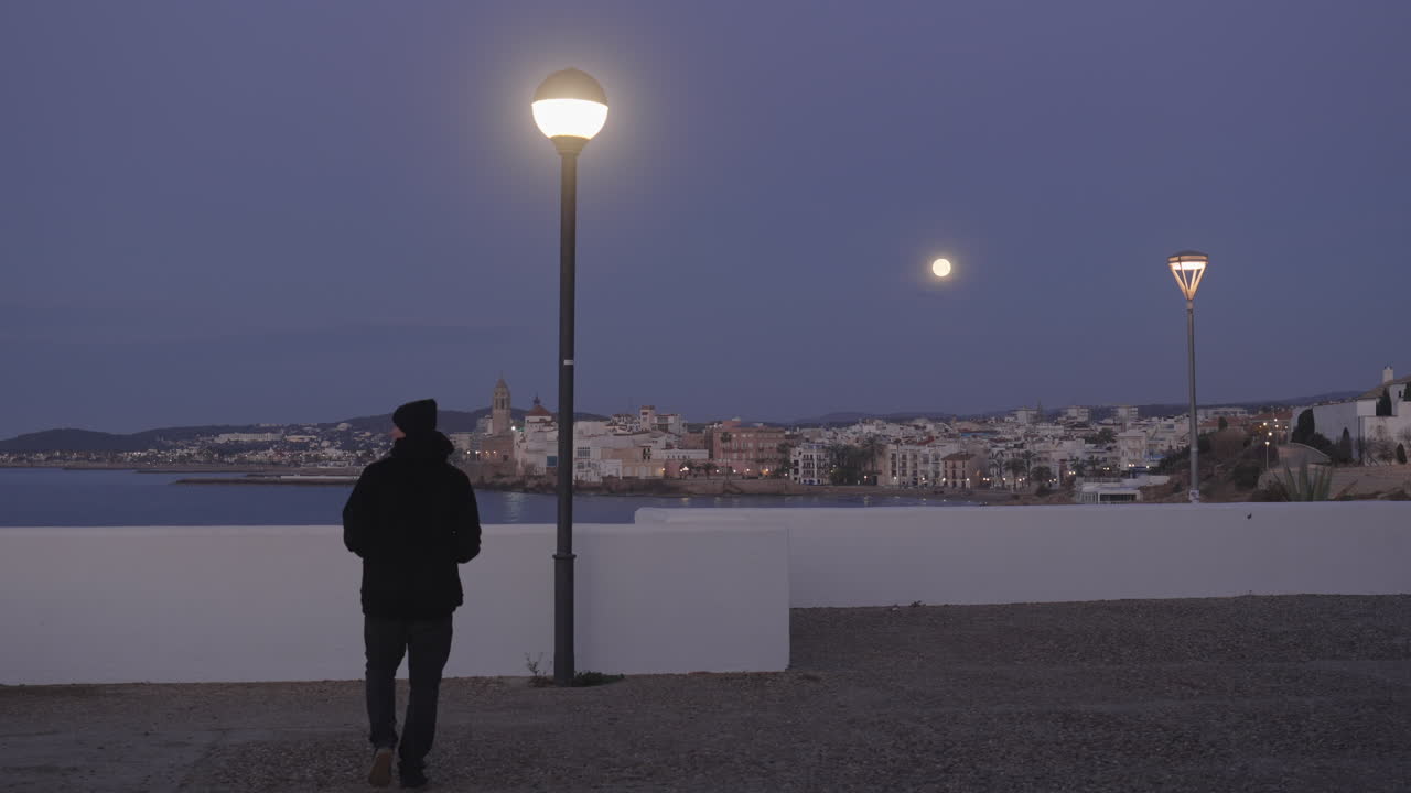 paisaje urbano, el hombre entra, toma fotos de la ciudad costera, mientras la luna brilla arriba