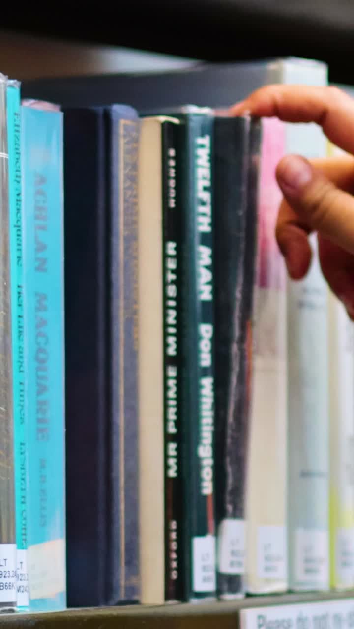 eligiendo a mano un libro de la estantería de la biblioteca