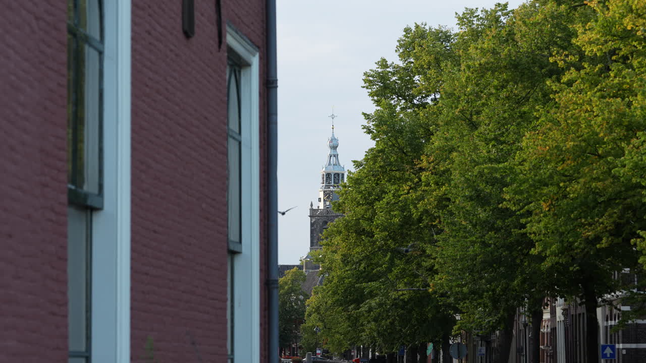 Rød mursteinsfasade av kirke med frodige grønne trær i det fjerne i Gouda, Nederland
