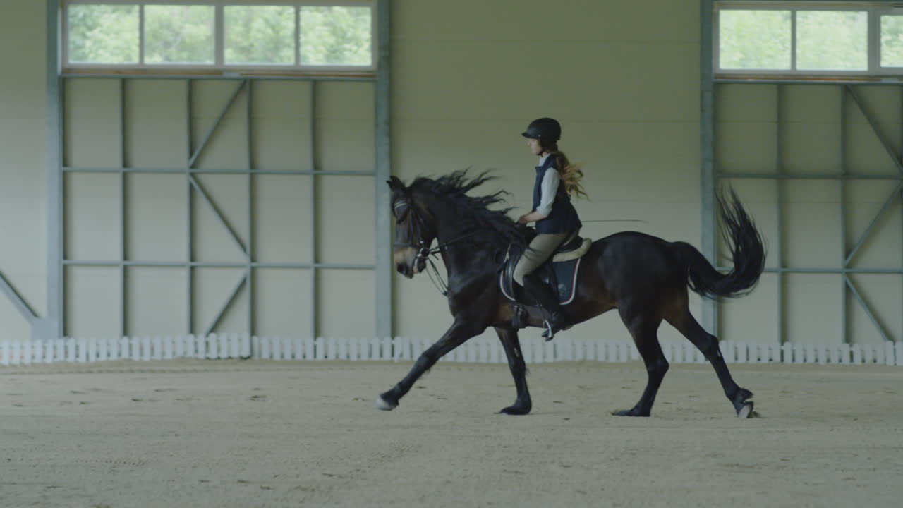 A woman riding a horse in an indoor equestrian arena