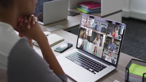 mid section of african american woman having a video conference on laptop with colleagues at office