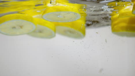 adding slices of lemon in fresh water with bubbles, natural citrus flavor