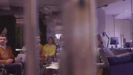 muslim woman in a modern open space coworking office giving a presentation to team. middle eastern arab businesswoman in creative startup office. disabled businessman in a wheelchair on team meeting