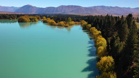 aerial flying over the scenic shoreline of a glacial lake in new zealand