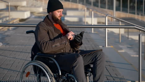 man in wheelchair using smartphone outdoors