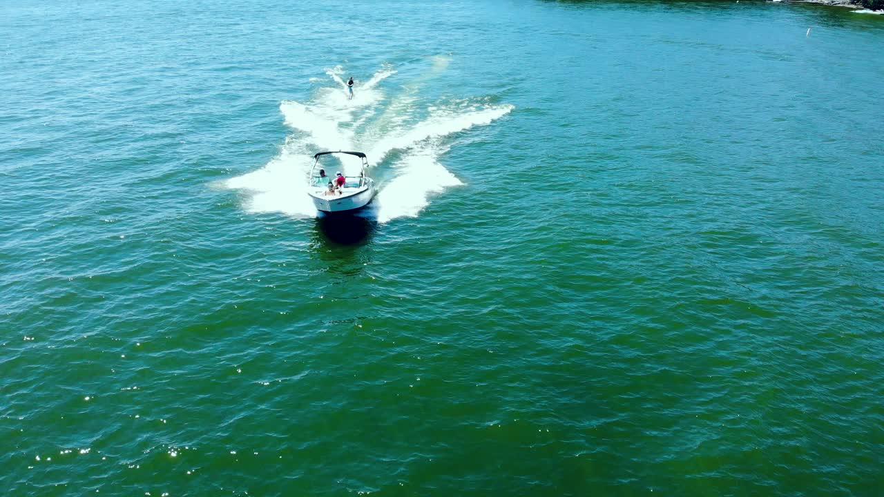 vista aérea de un bote a motor de alta velocidad tirando de un esquiador acuático
