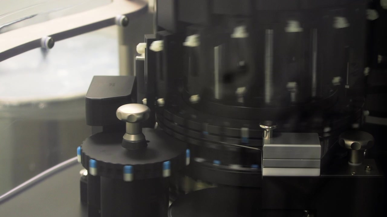 Automated pharmaceutical manufacturing equipment processing medical containers inside a modern production facility. Precision industrial machinery used for pharmaceutical manufacturing, quality contro