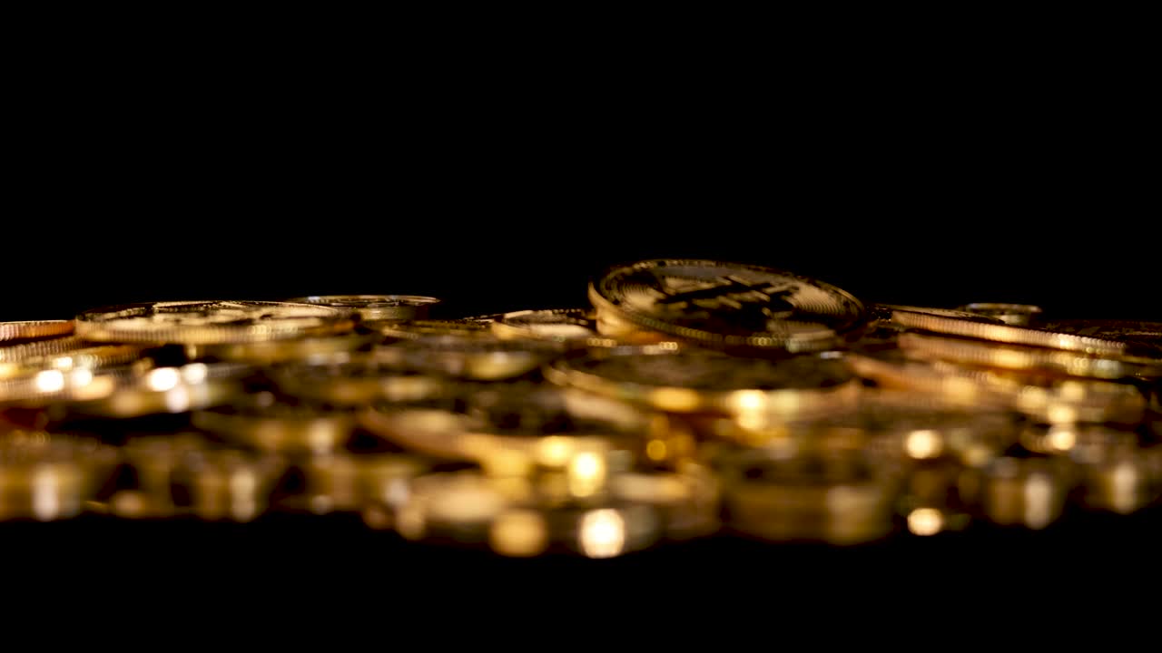 Camera rack focuses from blurred to sharp gold coins, dramatic lighting, black background, cinematic style