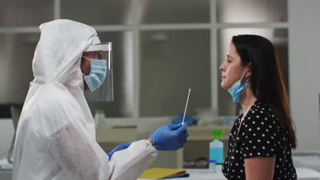 trabajador médico con ropa de protección tomando una prueba de hisopo de una paciente femenina