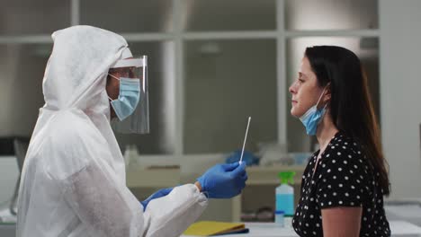 medical worker in protective clothing taking swab test from female patient