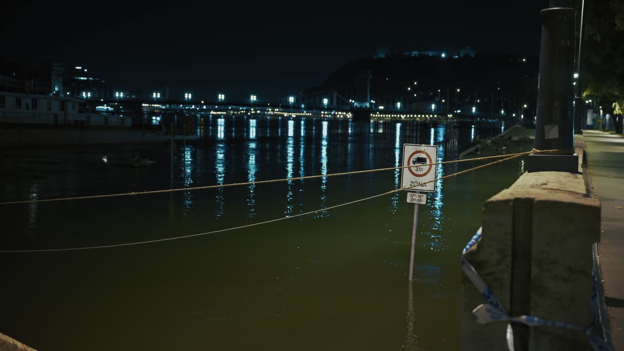 Night view of a city river with a flood warning sign