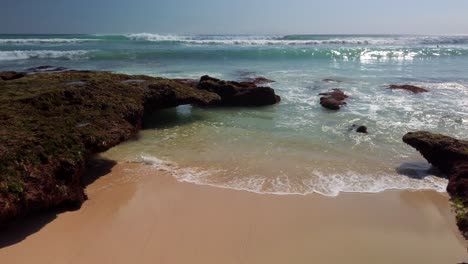 Stable-4k-view-of-Uluwatu-Beach-in-Bali-Indonesia,-sand-and-waves-rolling-in