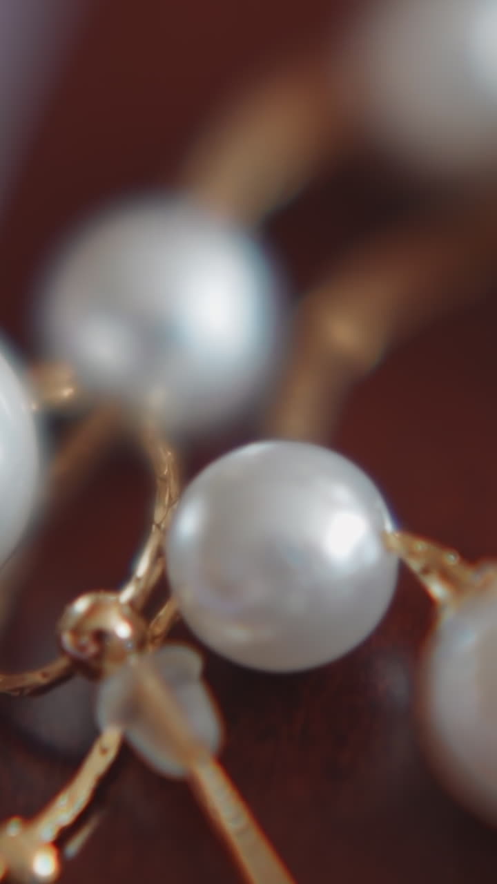 Golden earring with sparkling pearls and chain on table extreme closeup. Bijouterie and accessory for bride style. Wedding ceremony tradition and trends