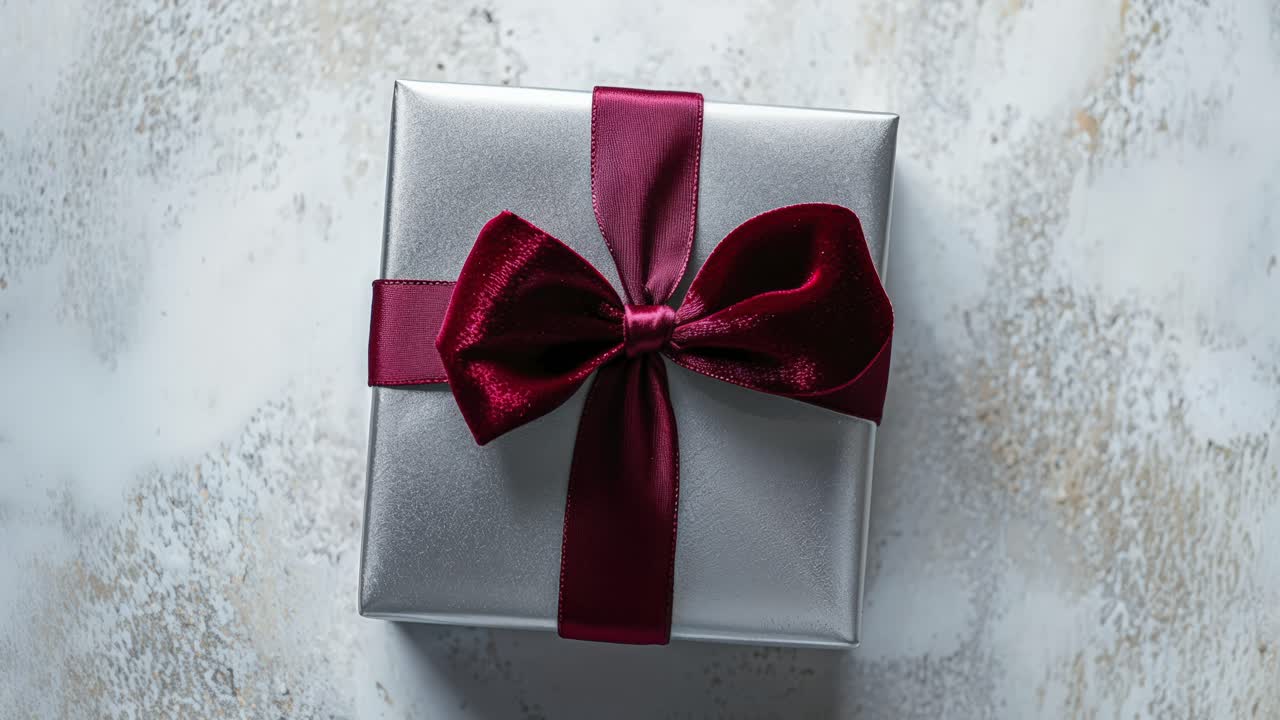 A silver gift box with a red bow