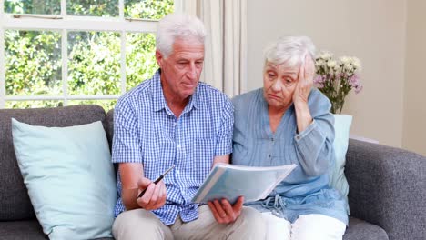 worried senior couple looking at document