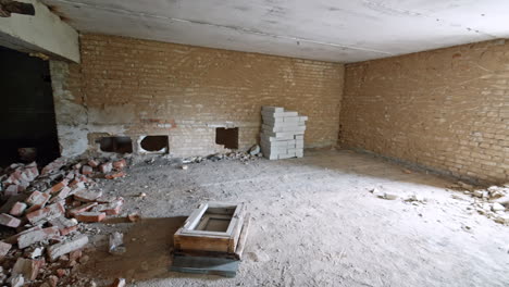 a pile of broken old bricks inside the room of a building. a stack of white new bricks is at the wall.