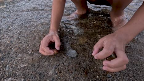 Enjoy a tranquil moment at sunset as hands sift through cool water and pebbles on the beach, revealing hidden treasures beneath the surface. Nature's beauty unfolds in this relaxing activity