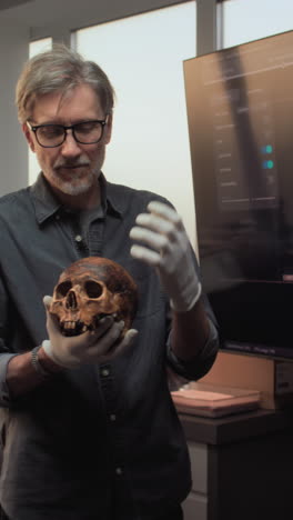 expert examining a human skull in a museum or lab setting