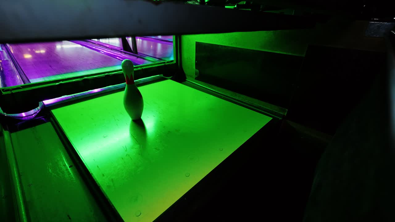 Momento emozionante in cui una palla da bowling colpisce i birilli sotto riflessi neon colorati