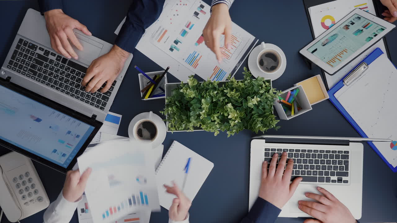 Vista dall'alto del lavoro di squadra aziendale seduto al tavolo della scrivania che pianifica gli investimenti di gestione