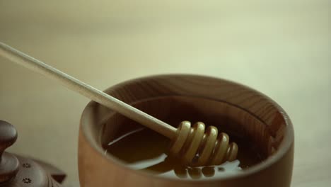 honey dripping, pouring from honey dipper in wooden bowl. close-up. healthy organic thick honey dipping from the wooden honey spoon, closeup. 4k uhd video footage. slow motion