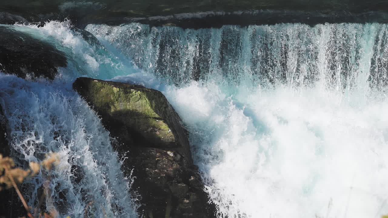 imágenes de la naturaleza de una cascada, con agua blanca cayendo sobre las rocas oscuras, creando una exhibición del poder de la naturaleza