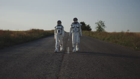 children in astronaut suits walking down a country road