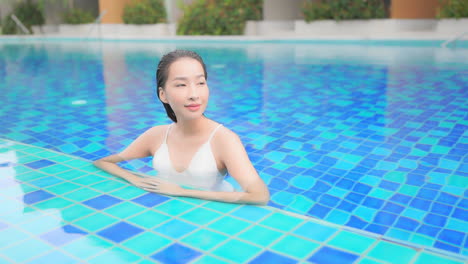 sexy exotic woman enjoying in water of blue swimming pool on luxury vacation, full frame slow motion