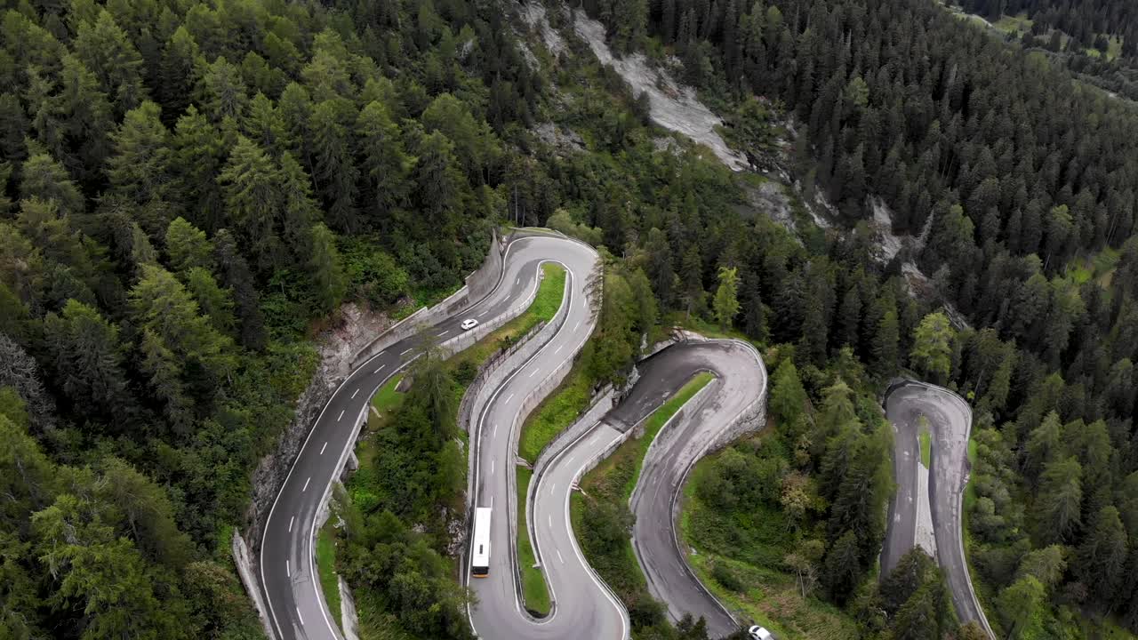 vista aérea de los giros del paso de maloja en engadin, suiza con coches y un autobús amarillo que sube y baja por la carretera