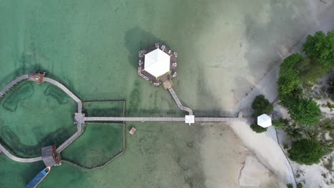 vista desde arriba de un puente de madera y un muelle en un complejo tropical con arena y agua turquesa en la isla de leebong en belitung, indonesia